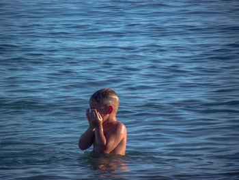 Portrait of shirtless boy swimming in sea