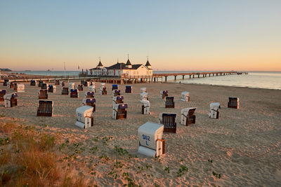 People on beach against clear sky during sunset