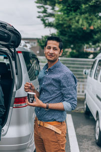 Portrait of man standing in car