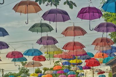 Low angle view of umbrellas hanging against sky in city