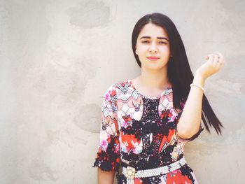 Portrait of young woman standing against wall