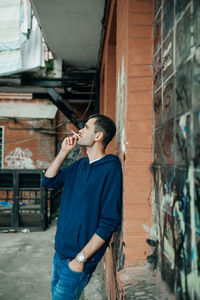 Full length of young man standing against building