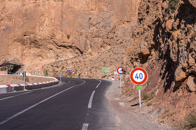 Asphalt road with markings and speed limit signs through mountain