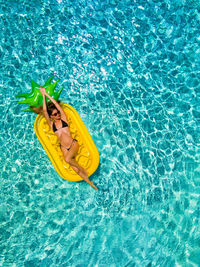 Directly above shot of woman on pool raft floating in swimming pool