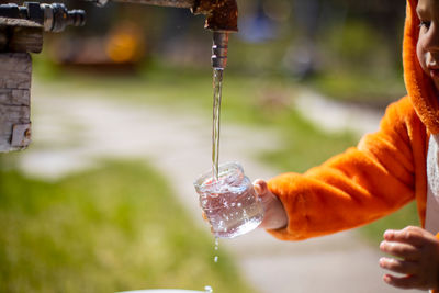 Faceless child plays with water in water tap outdoor person