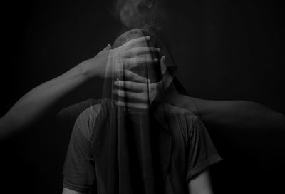 Portrait of young man standing against black background