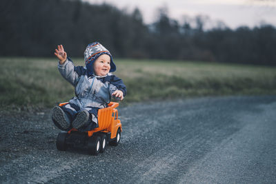 Cute boy sitting on toy truck