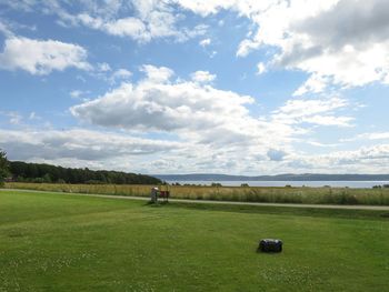 Scenic view of grassy field against cloudy sky