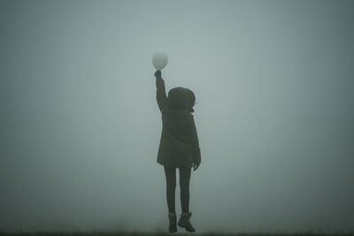 Rear view of woman holding balloon in fog