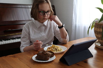 Full length of woman sitting on table at home