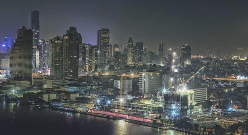 Illuminated buildings in city against sky at night