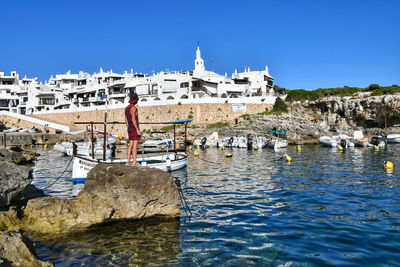 Buildings by sea against clear sky