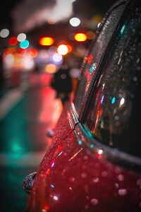 Close-up of wet car against illuminated christmas lights