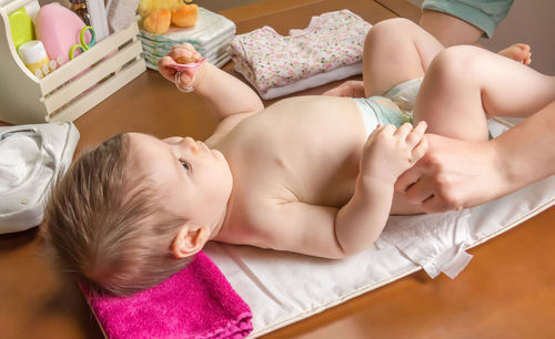 Woman changing diaper of baby girl at home