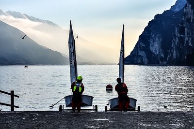 Rear view of men with sailboats entering in river