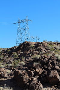 Low angle view of electricity pylon against blue sky