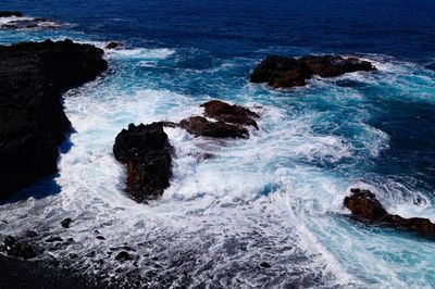 High angle view of waves splashing and crashing  on and over rocks white water surf 