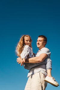 Low angle view of a smiling friends against blue sky