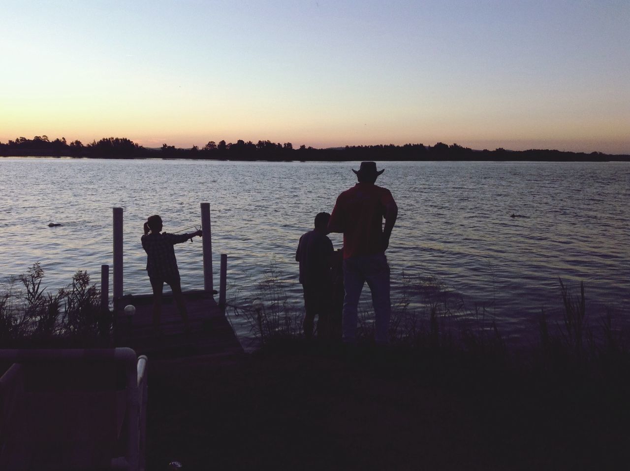 water, silhouette, men, sunset, clear sky, copy space, lifestyles, leisure activity, tranquility, tranquil scene, standing, rear view, lake, scenics, beauty in nature, togetherness, nature, sea