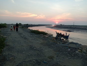 People on beach against sky during sunset