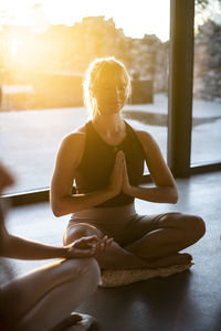 Woman with hands clasped practicing prayer pose while meditating at retreat center