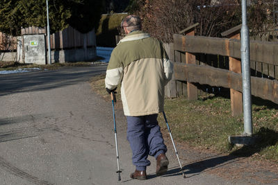 Rear view of man walking on footpath in city