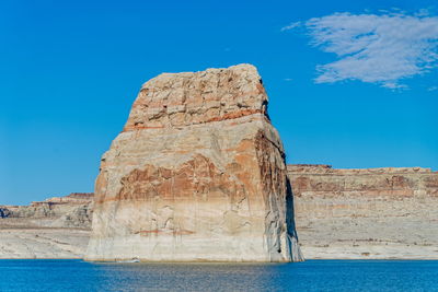 Rock formation by sea against blue sky