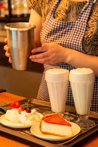 The waiter prepares an order for cafe visitors. delicious desserts and drinks at home coffee shop