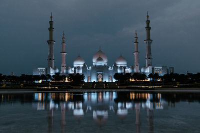 Reflection of illuminated mosque in lake at night