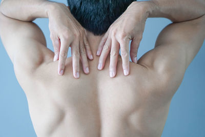 Rear view of shirtless mid adult man against blue background