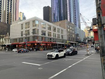 Cars on city street by buildings