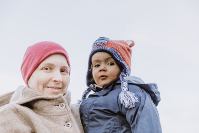 Portrait of smiling woman with daughter against clear sky during winter