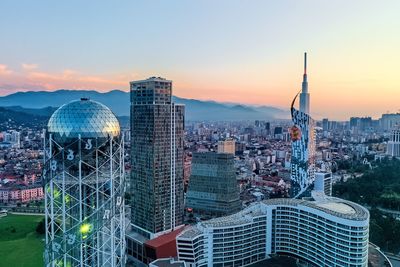 Modern buildings in city against sky during sunset