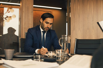Serious male financial advisor reviewing documents at legal office
