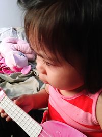 Close-up of cute girl playing toy guitar at home