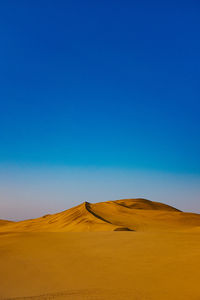 Scenic view of desert against clear blue sky