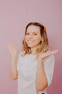 Portrait of a smiling young woman against pink background