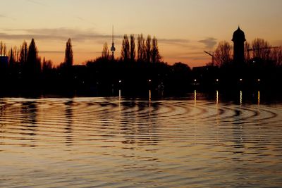 Silhouette trees by lake against sky during sunset