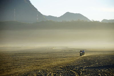 People riding motorcycle on field during foggy weather