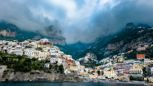 Aerial view of townscape by sea against sky