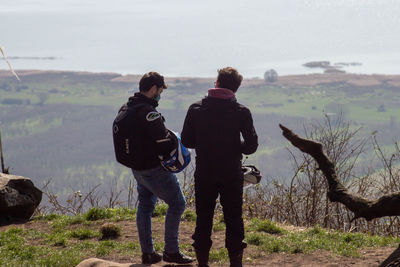 Rear view of men standing on land against sky