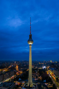 Communications tower in city against sky at night