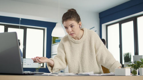 Portrait of young woman using mobile phone while sitting at home