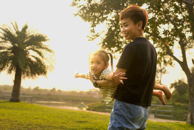 Side view of boy holding hands against trees