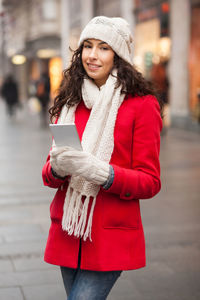 Portrait of young woman using smart phone while standing on city street