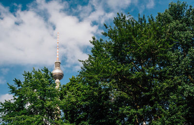 Low angle view of communications tower against cloudy sky