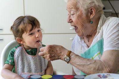 Grandmother feeding granddaughter in the kitchen