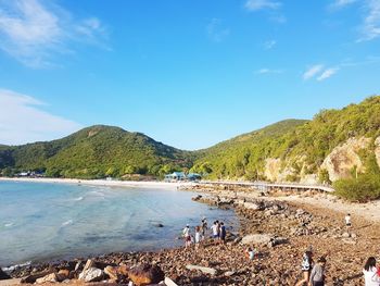 People at beach against blue sky