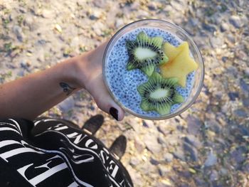 Low section of woman having drink in glass while standing on field