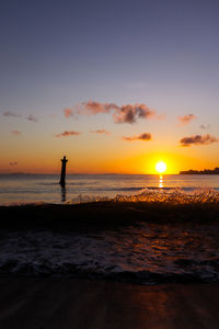 Silhouette people on beach against sky during sunset